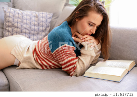 Ypung woman reading a book on the couch Ypung woman reading a book on the couch 113617712