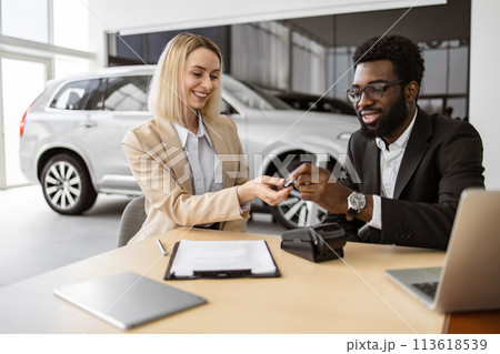 Happy Caucasian young woman sitting at table and receives keys of SUV car. Happy Caucasian young woman sitting at table and receives keys of SUV car. 113618539
