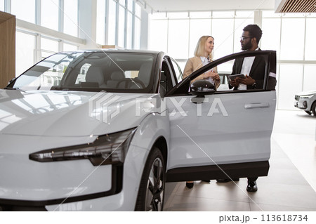 Confident man showing to potential buyer automobile. Confident man showing to potential buyer automobile. 113618734