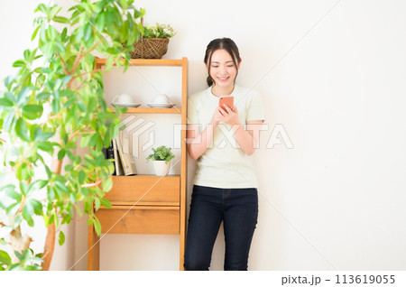 壁際に立ってスマホを見る若い女性 壁際に立ってスマホを見る若い女性 113619055