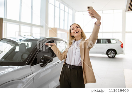 Successful businesswoman taking selfie using smartphone in car service. Successful businesswoman taking selfie using smartphone in car service. 113619409