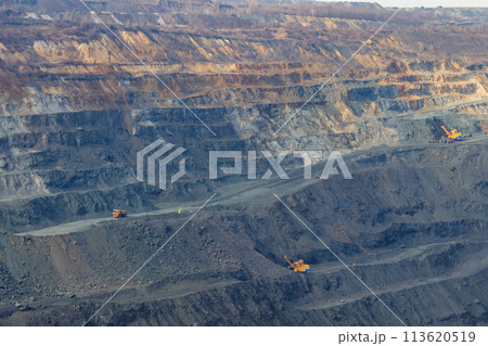 Huge iron ore quarry with working dump trucks and excavators 113620519