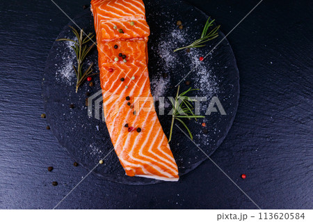 Raw salmon fillet with spices on black slate. Top view Raw salmon fillet with spices on black slate. Top view 113620584