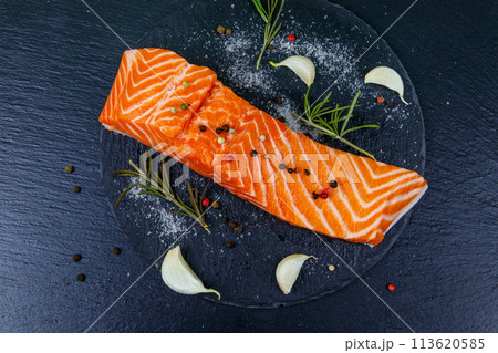 Raw salmon fillet with spices on black slate. Top view 113620585