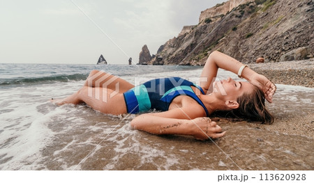 Woman summer travel sea. Happy tourist in blue bikini enjoy taking picture outdoors for memories. Woman traveler posing on the beach surrounded by volcanic mountains, sharing travel adventure journey Woman summer travel sea. Happy tourist in blue bikini enjoy taking picture outdoors for memories. Woman traveler posing on the beach surrounded by volcanic mountains, sharing travel adventure journey 113620928