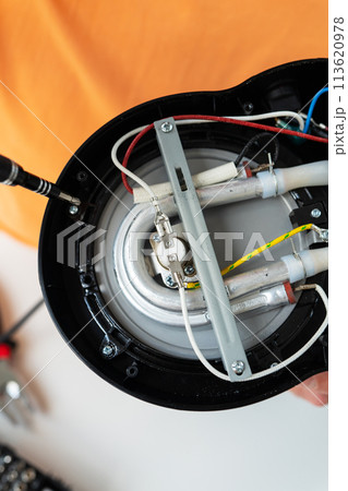 Close-up of hands repairing a speaker, intricate wiring and components visible. Close-up of hands repairing a speaker, intricate wiring and components visible. 113620978