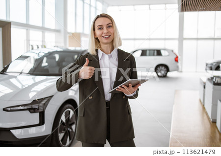Attractive young woman standing in front of car with digital tablet. Attractive young woman standing in front of car with digital tablet. 113621479