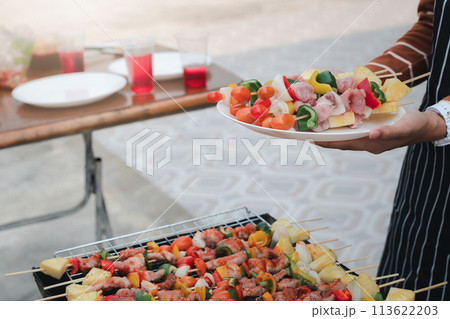 A woman with a barbecue plate at a party between friends. Food, people and family time concept. A woman with a barbecue plate at a party between friends. Food, people and family time concept. 113622203