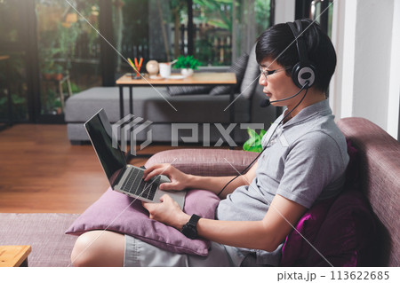 Businessman meeting online via video call on laptop in home office. Man wear headphone video calling or distance education e-leaning online course. 113622685