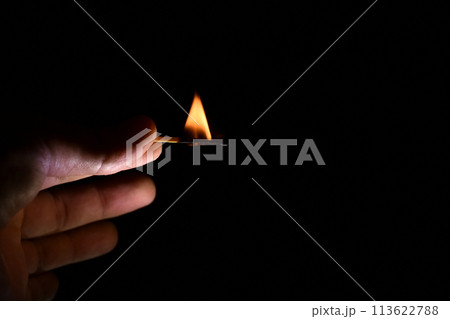 burning match in the fingers of a man close-up on a black background 113622788
