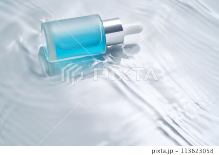 Bottles of cosmetics with a dropper in water on a blue background. 113623058