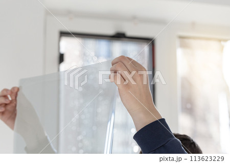 Installation of tinted film, foil in hands. Ultraviolet and energy afficiency concept. Installation of tinted film, foil in hands. Ultraviolet and energy afficiency concept. 113623229