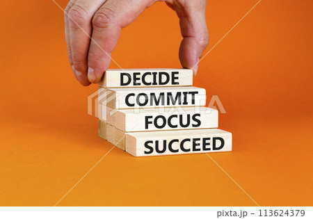 Decide commit focus succeed symbol. Concept word Decide Commit Focus Succeed on wooden block. Beautiful orange background. Businessman hand. Business decide commit focus succeed concept. Copy space. 113624379