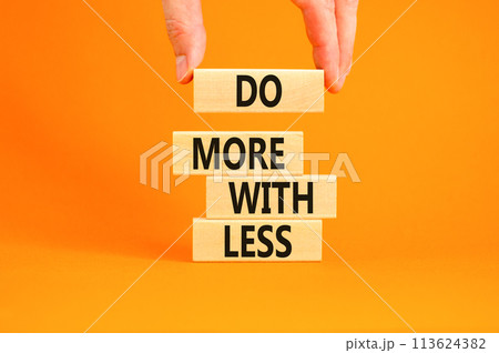Do more with less symbol. Concept word Do more with less on beautiful wooden block. Beautiful orange table orange background. Businessman hand. Business do more with less concept. Copy space. 113624382