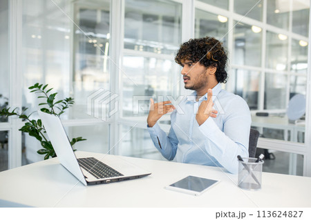 Young male professional gestures as he discusses or explains heat management in a bright, modern office setting, showcasing discomfort and resolution tactics. Young male professional gestures as he discusses or explains heat management in a bright, modern office setting, showcasing discomfort and resolution tactics. 113624827