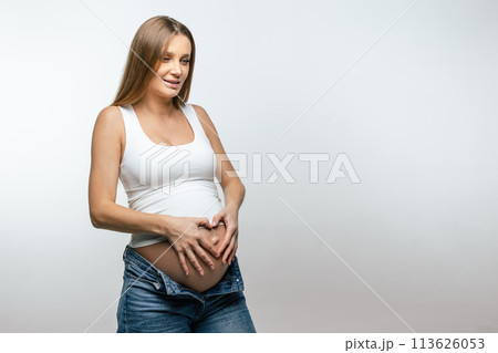 Fair-haired young pregnant woman holding her big belly Fair-haired young pregnant woman holding her big belly 113626053