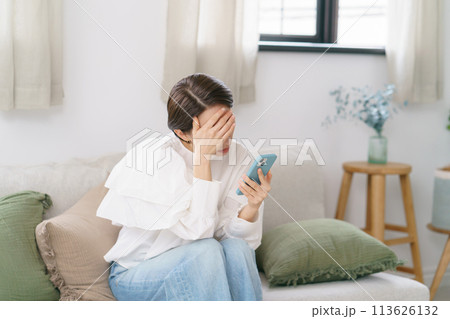 スマホを見て悩むミドル女性 113626132