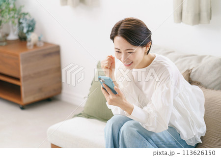 スマホを見て喜ぶ30代女性 113626150