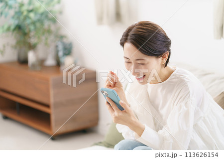 スマホを見て喜ぶ30代女性 113626154
