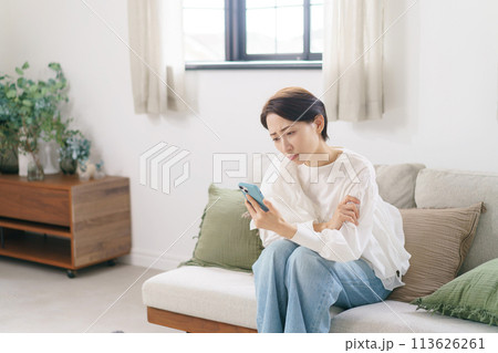 スマホを見て悩む30代女性 113626261