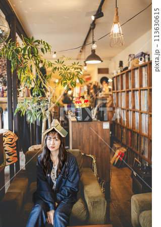 お洒落なアンティークカフェで本を頭にのせてリラックスしている女性 113630615