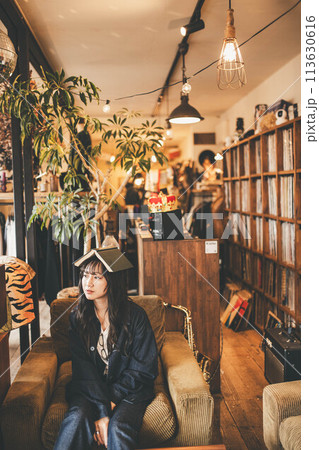 お洒落なアンティークカフェで本を頭にのせてリラックスしている女性 113630616