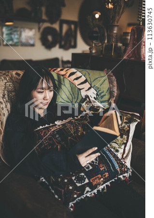 カフェの窓際の席でコーヒーを飲みながら休日に読書する若い女性 113630745