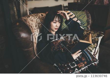 カフェの窓際の席でコーヒーを飲みながら休日に読書する若い女性 カフェの窓際の席でコーヒーを飲みながら休日に読書する若い女性 113630746