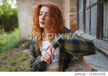 Redhaired woman posing next to old brick house Redhaired woman posing next to old brick house 113632208