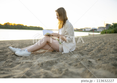 Woman reading book beach at sunset 113632227