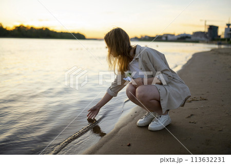 Woman touching water in river at sunset Woman touching water in river at sunset 113632231