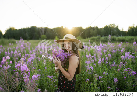 Portrait of smiling woman with flowers on meadow 113632274