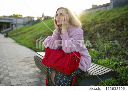 Serious woman sitting on bench at sunrise 113632306