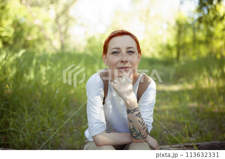 Portrait of smiling woman sitting on grass Portrait of smiling woman sitting on grass 113632331