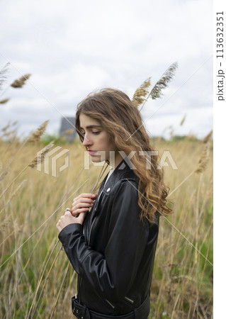 Portrait of woman standing in field on windy day Portrait of woman standing in field on windy day 113632351