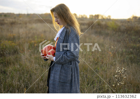 Side view of woman holding pumpkins in field 113632362