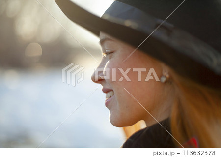 Portrait of smiling woman in hat at sunset Portrait of smiling woman in hat at sunset 113632378