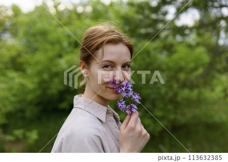 Portrait of smiling woman smelling lilac flower 113632385