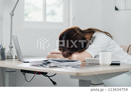 Exhausted professional takes a quick power nap at her desk, amidst a busy work schedule. 113634759