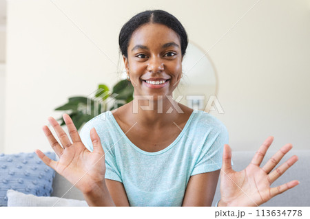 Young biracial woman smiles brightly at home on a video call 113634778