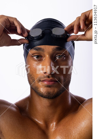 Young biracial male swimmer adjusts his swimming goggles 113634917