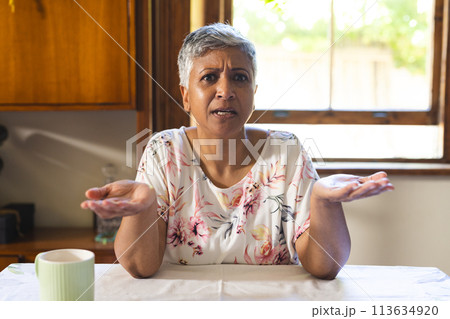 A mature biracial woman looks puzzled at home on a video call 113634920