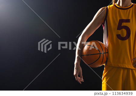 Athlete in basketball uniform holds a ball on a black background, with copy space Athlete in basketball uniform holds a ball on a black background, with copy space 113634939