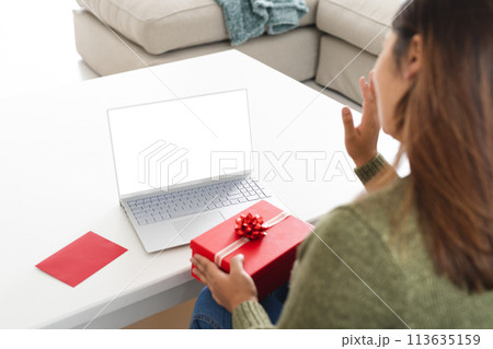 Young biracial woman holding a gift, with copy space 113635159