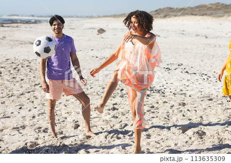 Young biracial couple enjoys a soccer game on the beach Young biracial couple enjoys a soccer game on the beach 113635309