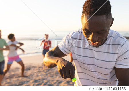 Young African American man prepares to blow bubbles on the beach 113635388
