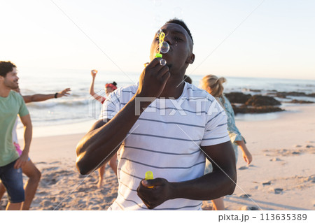Young African American man blows bubbles on the beach Young African American man blows bubbles on the beach 113635389