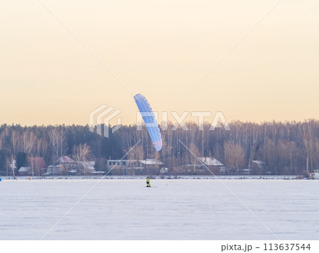 Kite surfer ride on snowboard. Snowkiting in the snow on frozen lake. 113637544