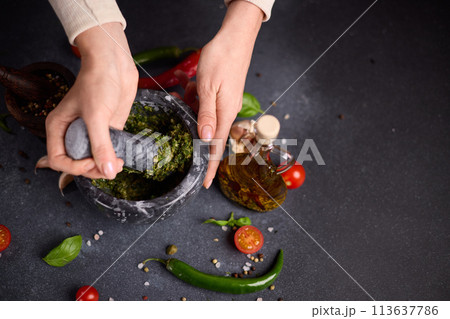 woman pounding in a stone marble mortar green sauce chopped ingredients - capers, fennel and basil woman pounding in a stone marble mortar green sauce chopped ingredients - capers, fennel and basil 113637786