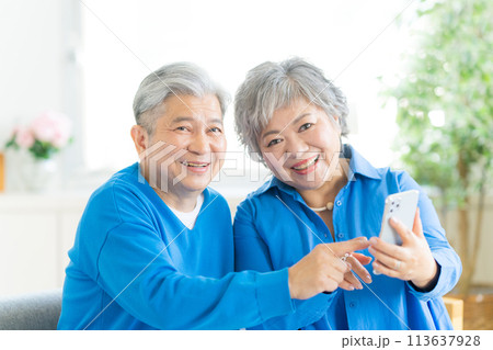 リビングでスマホを見るシニア夫婦 113637928